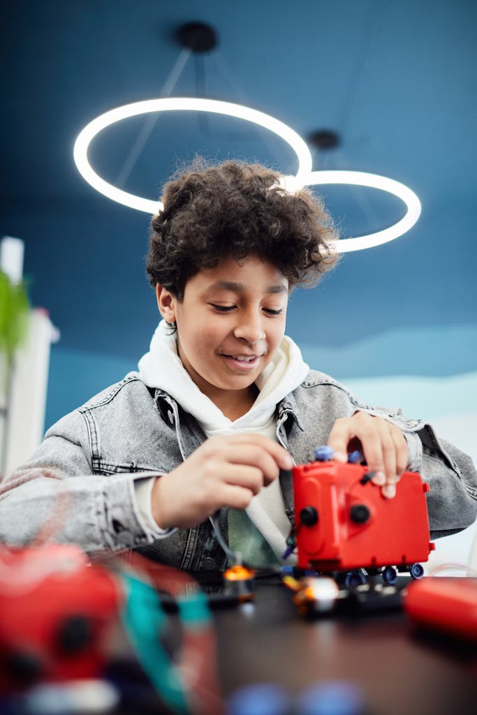 A teenage boy focusing on assembling a robotic project indoors at school.